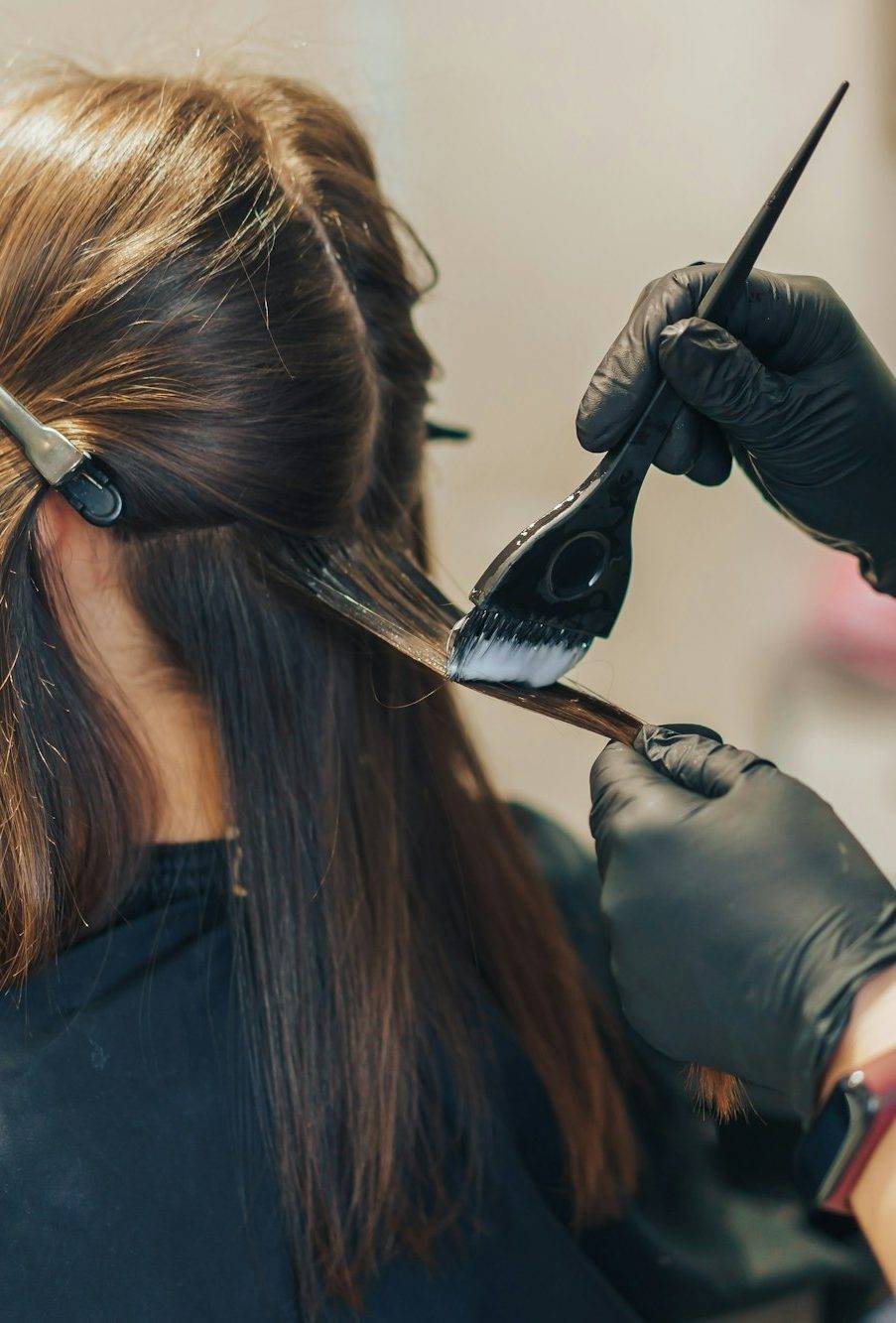 hair stylist dyes hair with a brush with foil