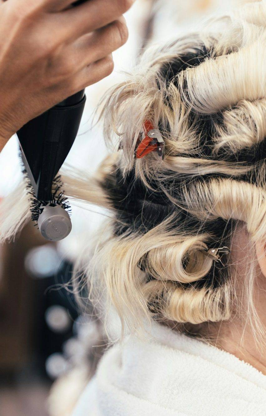 Unrecognizable hairdresser doing a permanent for a client